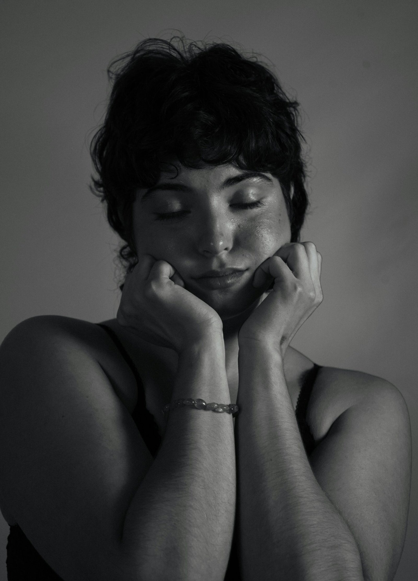 Moody black and white portrait of a woman with eyes closed, conveying deep emotion.