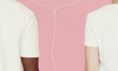 Two people connected by earphones against a pink background.